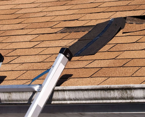 Ladder leading to missing shingles on roof