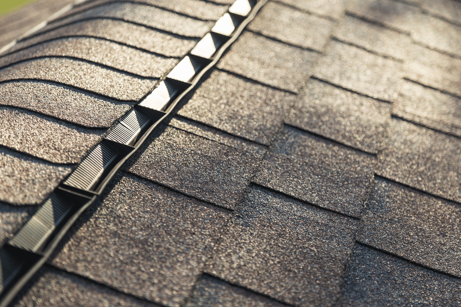 A close-up of ridge cap shingles showing signs of wear and damage. 