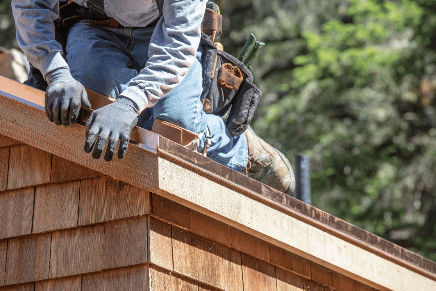 A roofer installing ridge cap shingles on a roof. 