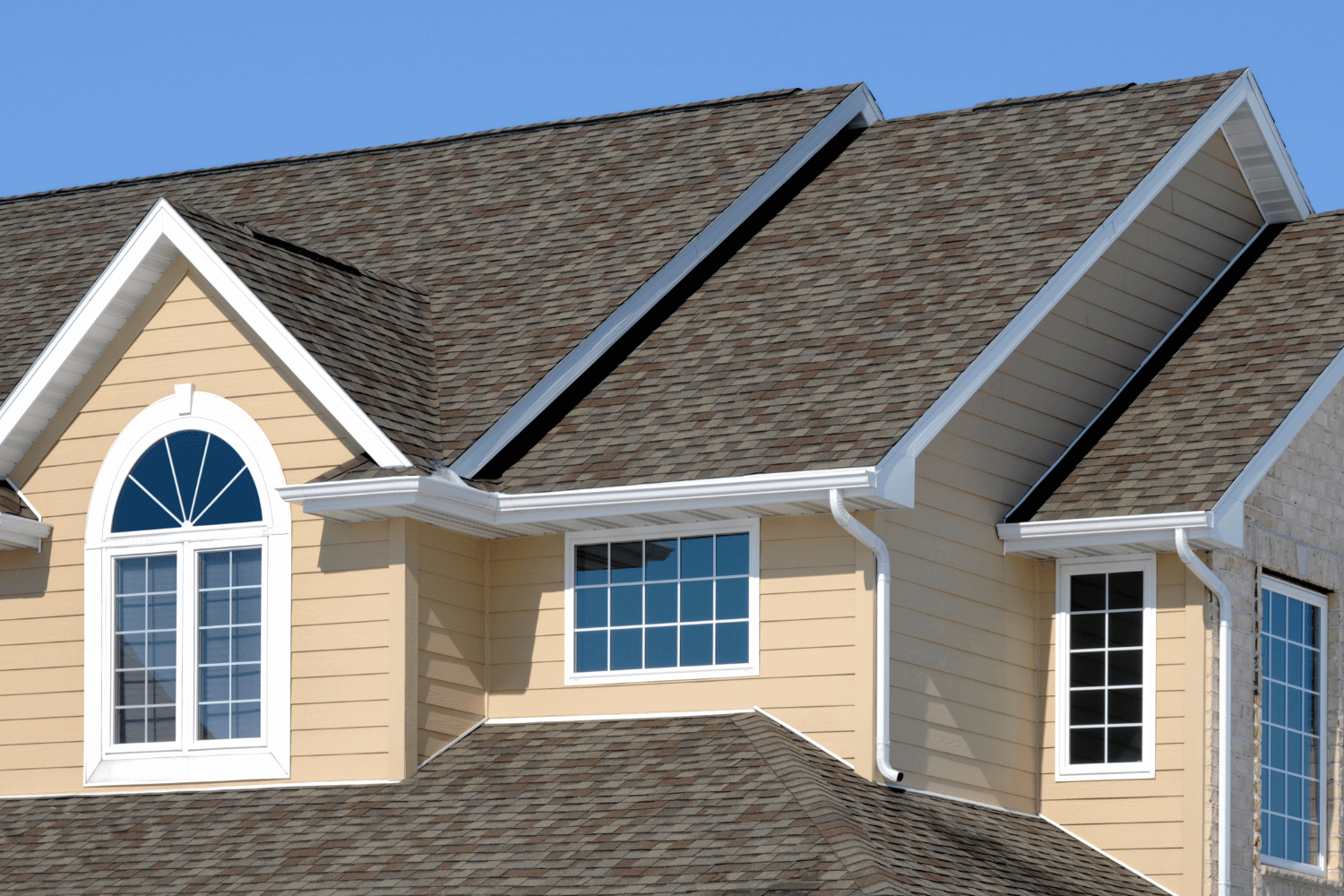 An attractive house with a newly installed asphalt shingle roof, demonstrating the benefits of asphalt shingle roofs. 