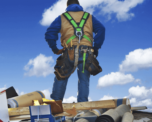 An image of a construction worker inspecting a roof, preparing for a roof replacement.
