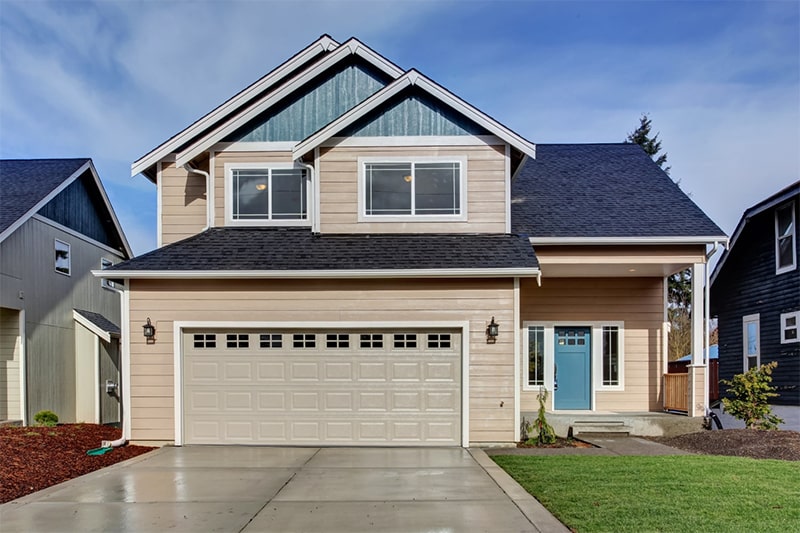 A two-story house featuring a garage and a spacious driveway.