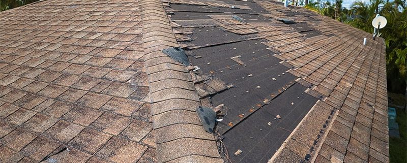 A roof featuring a compromised shingle alongside noticeable damage across the roof structure