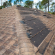 A roof featuring a compromised shingle alongside noticeable damage across the roof structure