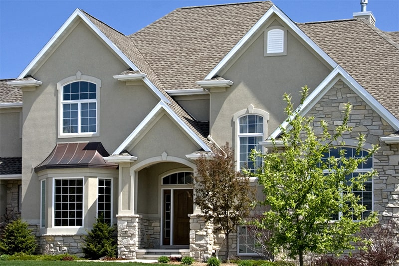 A beautiful residence with elegant stone accents and a generous front yard, showcasing a welcoming atmosphere