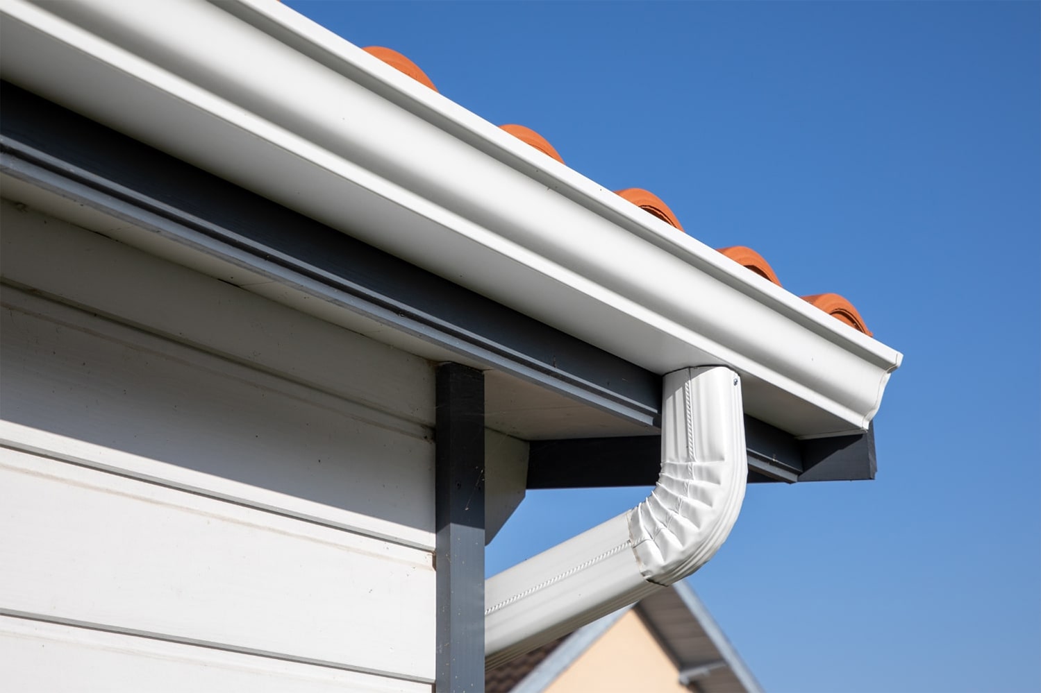 A close-up view of a house gutter, showcasing its structure and details against the backdrop of the building.