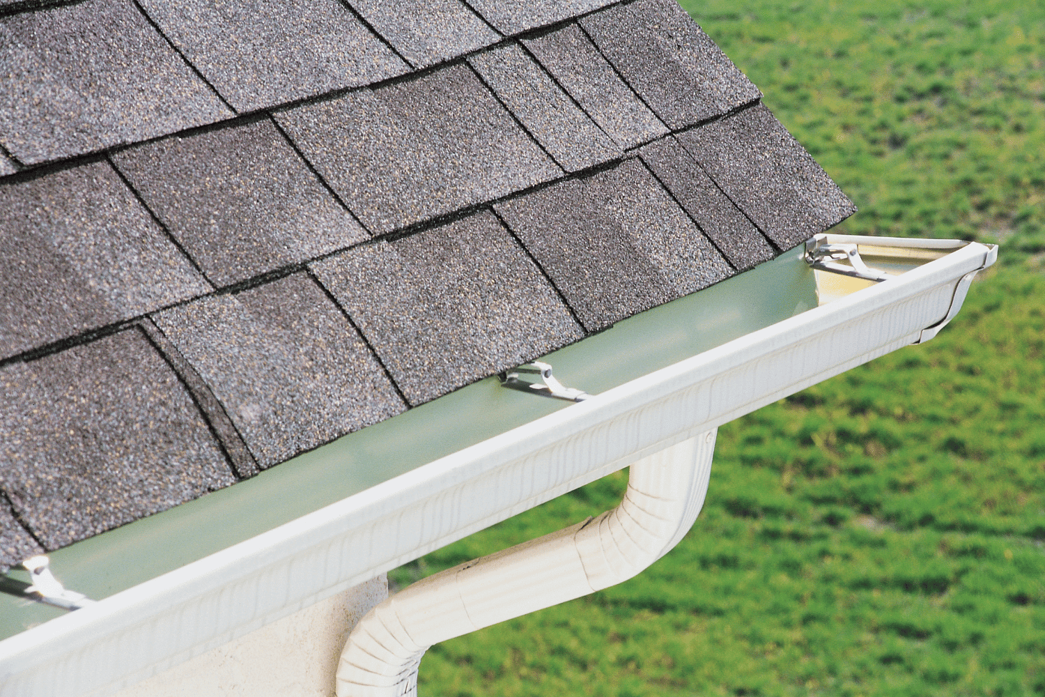 A roofing contractor installing new gutters after completing a roof replacement. 