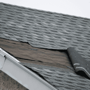 A construction worker repairing a wind-damaged roof, showcasing the repair process.