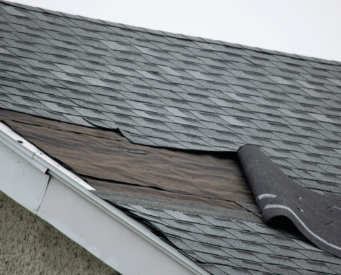 A construction worker repairing a wind-damaged roof, showcasing the repair process.