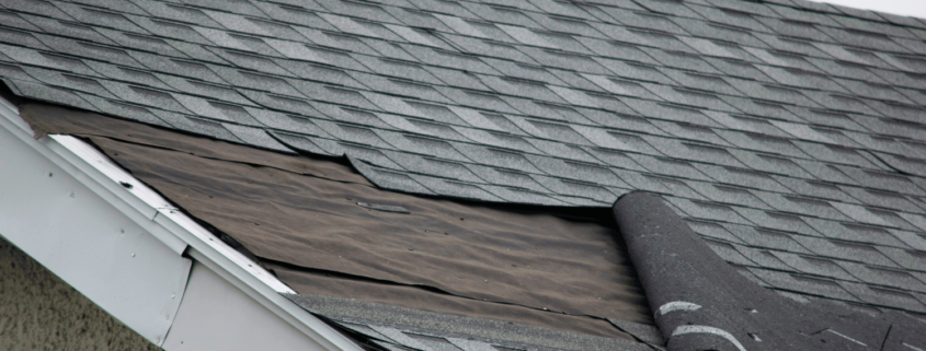 A construction worker repairing a wind-damaged roof, showcasing the repair process.