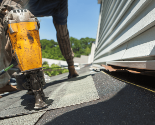 An assortment of essential roofing tools including a putty knife and roofing nails.