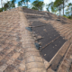 An image showing visible signs of wind damage to a roof, including missing and damaged shingles.