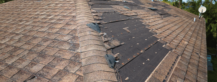 An image showing visible signs of wind damage to a roof, including missing and damaged shingles.