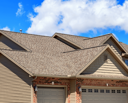 A family standing in front of their home with an asphalt shingle roof.