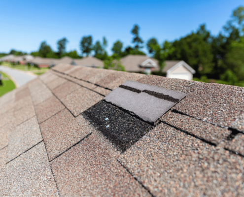 A house with a visibly damaged roof indicating the need for a roof replacement.