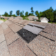 A house with a visibly damaged roof indicating the need for a roof replacement.