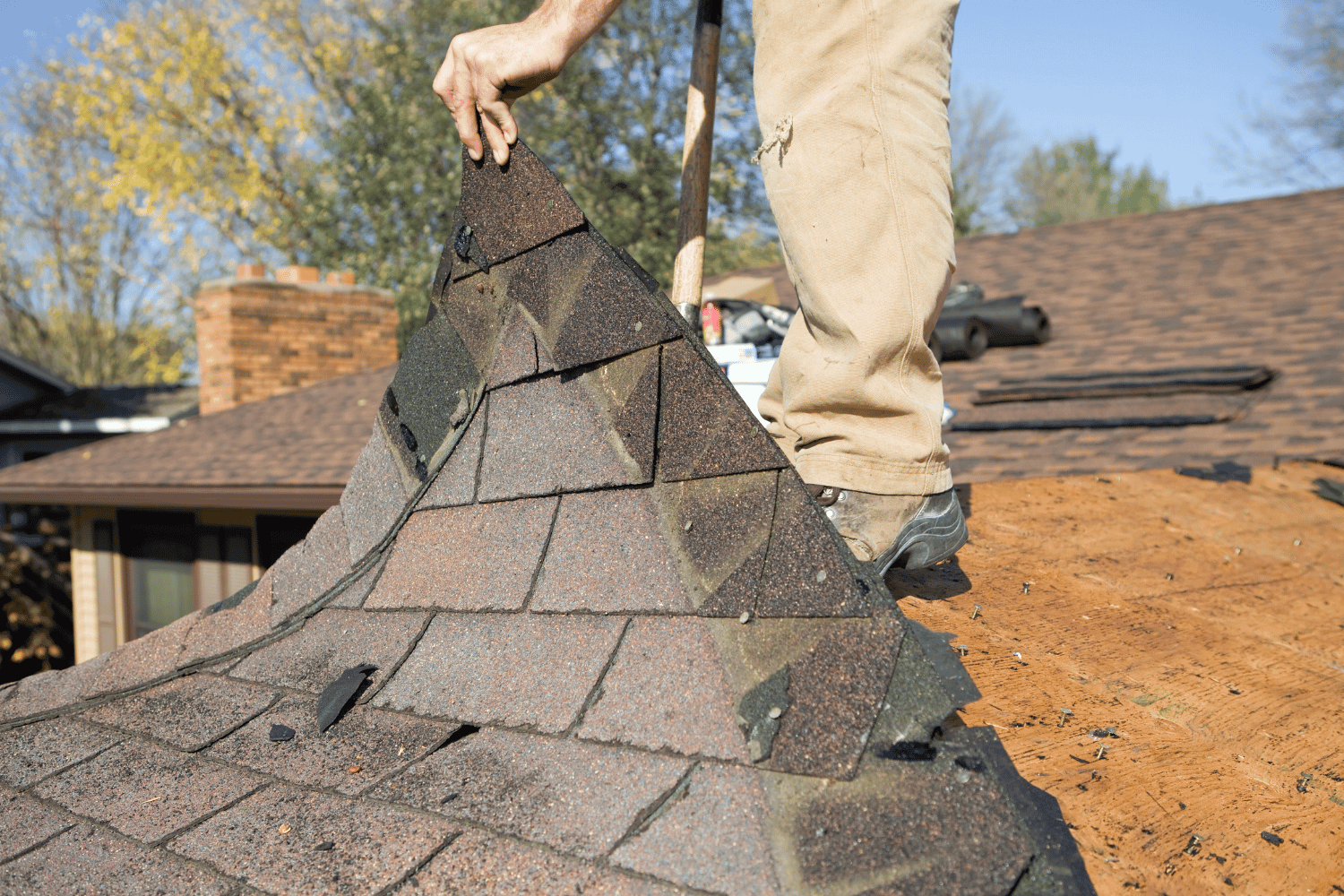 Workers removing old roofing materials during the roof replacement process.